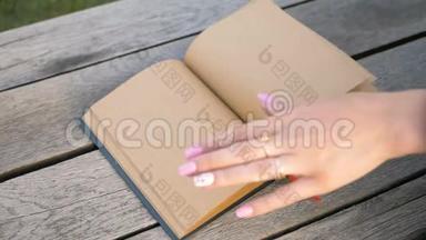 女`的手缓缓<strong>翻开</strong>一页干净的书.. 一本米色的笔记本。 手指上的环。